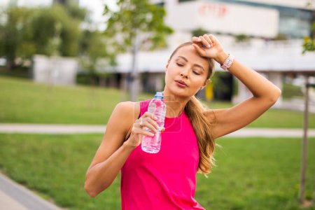 Photo for Woman drinking water after running outdoor, rehydration concept - Royalty Free Image