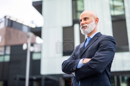 Foto de Retrato de un hombre de negocios de confianza con la cabeza rapada y barba blanca en una ciudad moderna - Imagen libre de derechos
