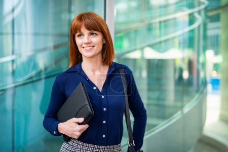 Téléchargez les photos : Femme d'affaires tenant une tablette sous son bras devant son bureau - en image libre de droit