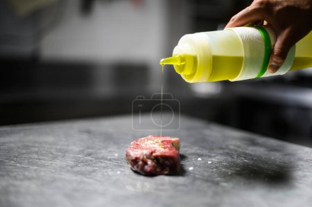 Photo for Chef pouring oil on a raw steak - Royalty Free Image