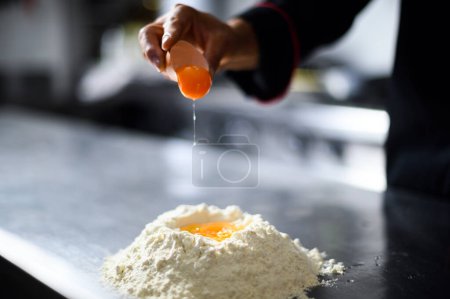 Photo for Front view of male hands breaking an egg into flour, making dough - Royalty Free Image