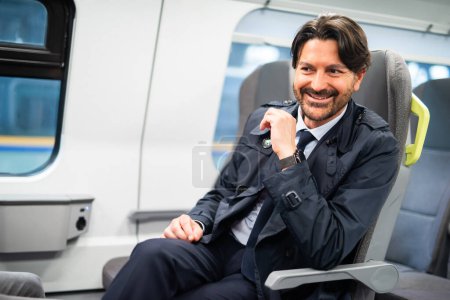 Photo for Smiling businessman sitting in a modern train - Royalty Free Image
