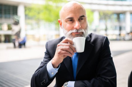 Photo for Senior stylish bald manager with white beard having a coffee outdoor - Royalty Free Image