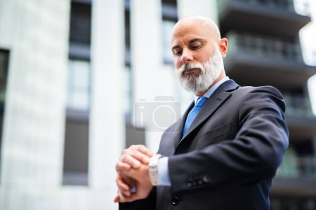 Photo for Businessman checking his wrist watch with a shocked expression - Royalty Free Image
