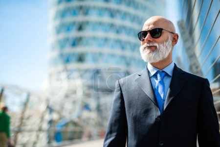 Photo for Mature bald stylish business man portrait with a white beard outdoor wearing sunglasses - Royalty Free Image