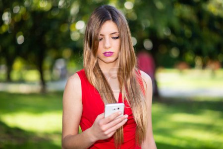 Foto de Joven hermosa mujer usando su teléfono inteligente en el parque, al aire libre - Imagen libre de derechos