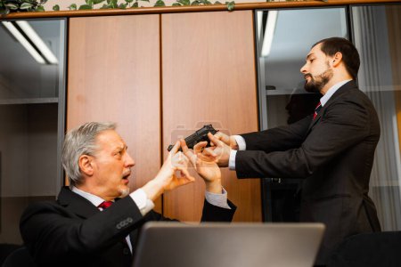 Photo for Businessman pointing a gun to his colleague due to the stress - Royalty Free Image