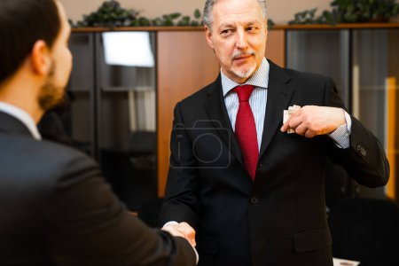 Photo for Senior manager putting a corruption tangent in his pocket - Royalty Free Image