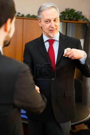 Photo for Senior manager putting a corruption tangent in his pocket - Royalty Free Image