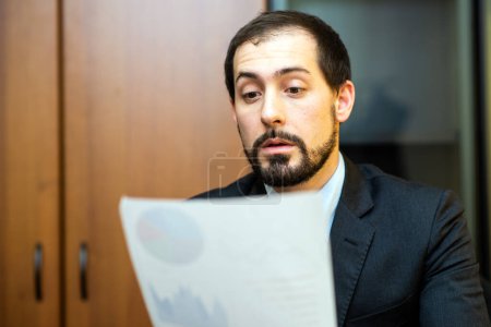 Photo for Businessman reading a document in his office - Royalty Free Image