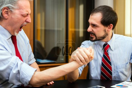 Photo for Two businessmen doing arm wrestling, younger one wins - Royalty Free Image