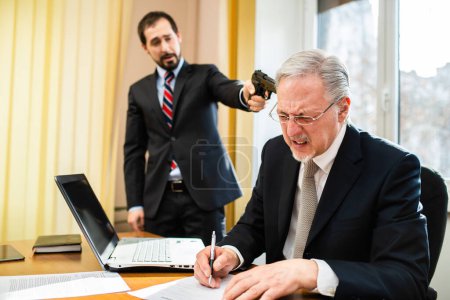 Téléchargez les photos : Homme d'affaires pointant une arme vers son collègue pour le forcer à signer un document - en image libre de droit