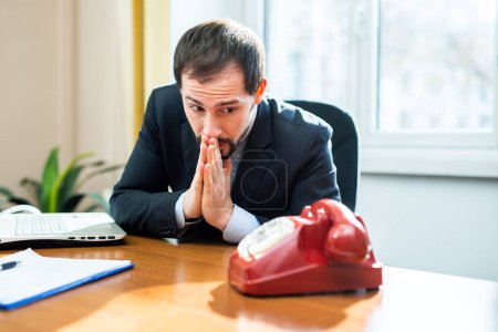Foto de Retrato del hombre de negocios mirando el teléfono y rezando por una llamada - Imagen libre de derechos