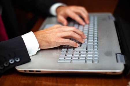 Téléchargez les photos : Gros plan sur les mains d'un homme d'affaires tapant sur un clavier d'ordinateur portable élégant - en image libre de droit