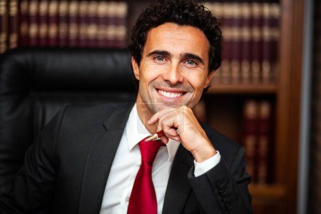 Téléchargez les photos : Portrait d'un homme d'affaires caucasien confiant et prospère. Professionnalisme souriant et exubérant dans un cadre de bibliothèque sophistiqué. Porter une tenue de travail avec un costume et une cravate. - en image libre de droit
