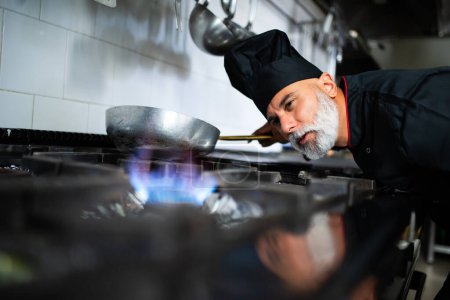 Photo for A chef with a beard is cooking food on a stove - Royalty Free Image