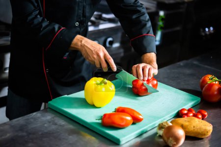 Foto de Chef meticulosamente corta verduras frescas en una tabla de cortar para la preparación de la comida - Imagen libre de derechos