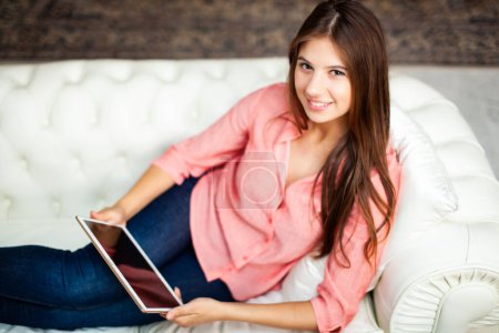Photo for Woman using a tablet while relaxing on the couch - Royalty Free Image