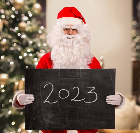 Photo for Santa Claus holding a blackboard in his hands with 2023 text - Royalty Free Image