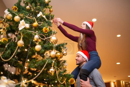 Photo for Couple decorating their christmas tree at home - Royalty Free Image