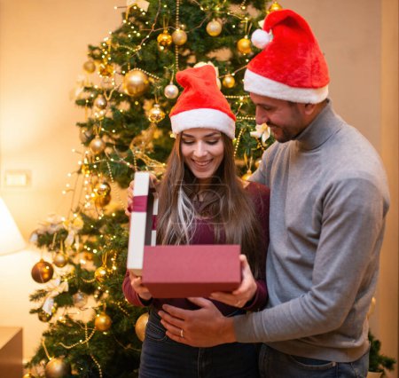 Téléchargez les photos : Jeune couple ouvrant un cadeau de Noël - en image libre de droit