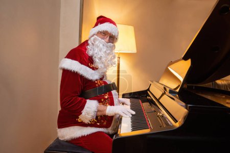 Photo for Santa Claus playing a piano indoors - Royalty Free Image