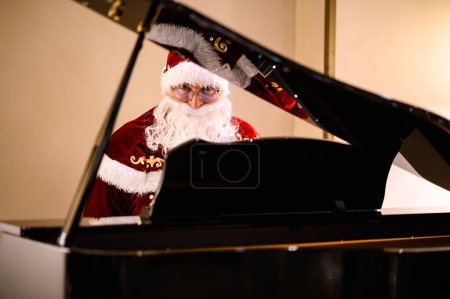 Foto de Santa Claus festivos disfrutando de la música en un piano de cola, mostrando alegría navideña - Imagen libre de derechos