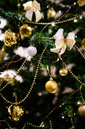Foto de Primer plano captura de los adornos brillantes y arcos dorados en un árbol de Navidad bellamente decorado - Imagen libre de derechos