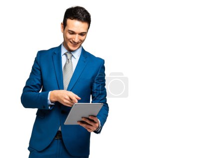 Photo for Cheerful and confident young adult businessman in a stylish business attire standing on a white background, smiling and using a digital tablet for work and communication - Royalty Free Image
