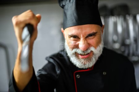 Foto de Chef masculino intenso vistiendo uniforme, mostrando frustración en un entorno de cocina profesional - Imagen libre de derechos