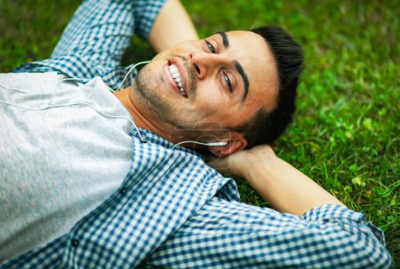 Photo for Young man relaxing on the grass in a park - Royalty Free Image