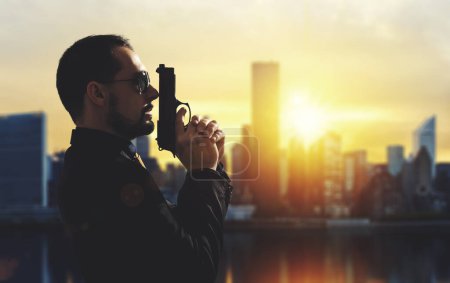 Photo for Mafia guy holding a gun in a metropolis at sunset - Royalty Free Image