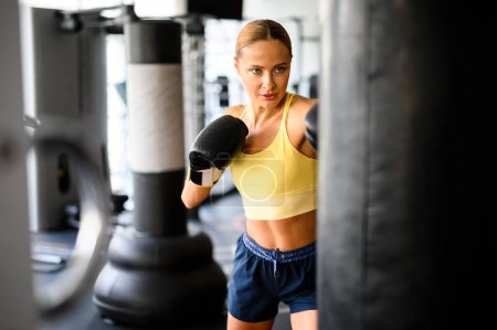 Foto de Mujer atlética en ropa deportiva se centra en su entrenamiento de boxeo en interiores - Imagen libre de derechos