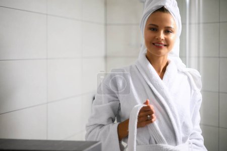Téléchargez les photos : Belle jeune femme en peignoir dans sa salle de bain - en image libre de droit