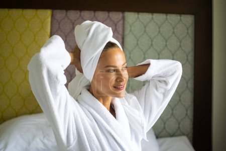 Foto de Mujer con una túnica blanca sonríe y se seca el pelo con una toalla - Imagen libre de derechos