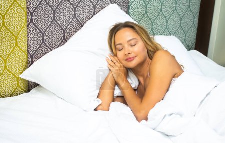 Foto de Mujer adulta joven disfrutando de un sueño reparador en una cama acogedora con telones de fondo vibrantes, que encarna la tranquilidad - Imagen libre de derechos