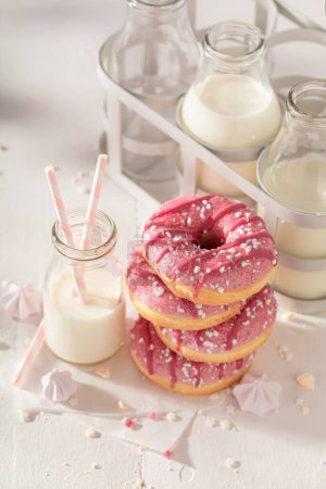 Fresh and tasty pink donuts for Fat Thursday. Served with milk. Most popular dessert.