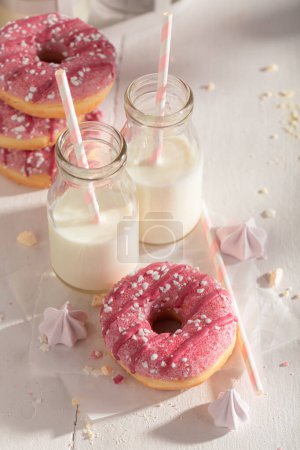 Leckere und hausgemachte rosa Donuts, serviert mit Milch in der Flasche. Serviert mit Milch. Beliebtestes Dessert.
