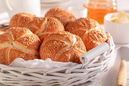 Petits pains Kaiser sucrés aux graines de sésame servis avec boisson. Petit déjeuner avec petits pains, beurre et miel.