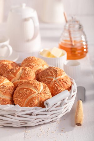 Rollos Kaiser saludables con semillas de sésamo horneadas para marrón dorado. Desayuno con rollos, mantequilla y miel.