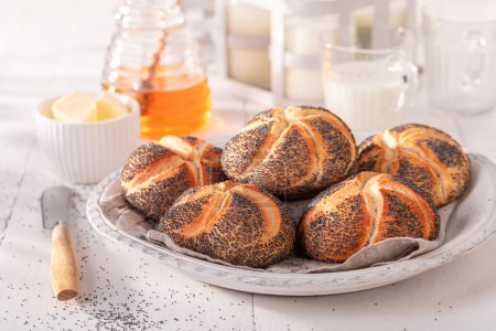 Tasty Kaiser buns with poppy seed for breakfast. Breakfast with buns, butter and honey.