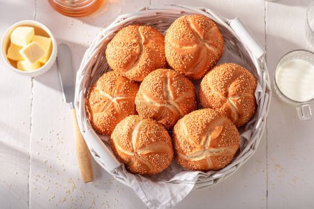 Petits pains Sweet Kaiser aux graines de sésame pour le petit déjeuner. Petit déjeuner avec petits pains, beurre et miel.