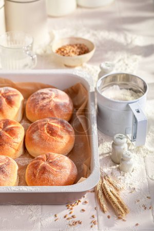 Hot and golden kaiser buns freshly baked in home bakery. Kaiser rolls  and ingredients in the bakery.