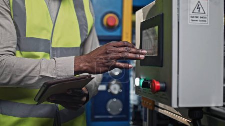 Close-up portrait of serious concerned African-American male at his work. Thoughtful handsome middle-aged man looks in his tablet and tap the electrician panel screen.