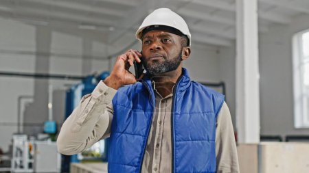 Téléchargez les photos : Portrait d'un homme afro-américain d'âge moyen occupé avec barbe parlant sur le nouveau smartphone moderne. Homme gesticulant et pointant vers une direction. Concept de patron. - en image libre de droit