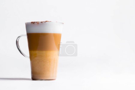 Latte macchiato in a tall glass on a white background. Cafe latte layered with milk in a high drinking glass. Minimalism. Copy space