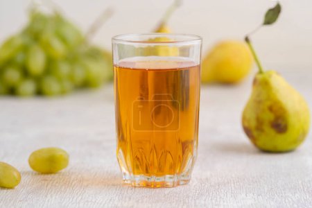 Foto de Jugo de peras y uvas en un vaso sobre fondo de madera blanca - Imagen libre de derechos
