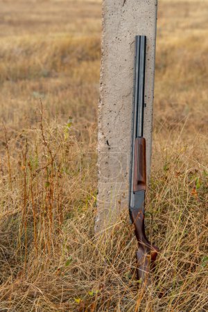 Foto de Escopeta de doble cañón con cartuchos, apoyada en un poste. Concepto de caza - Imagen libre de derechos
