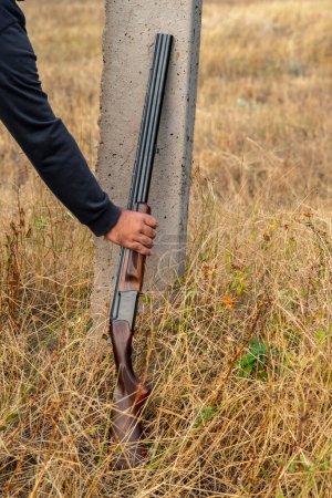 Téléchargez les photos : Fusil de chasse à double canon avec cartouches, appuyé contre un poteau. Concept de chasse - en image libre de droit