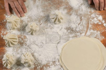 Téléchargez les photos : Chef cuisinier faire khinkali sur une table en bois. Préparation du processus repas géorgien. concept alimentaire. - en image libre de droit